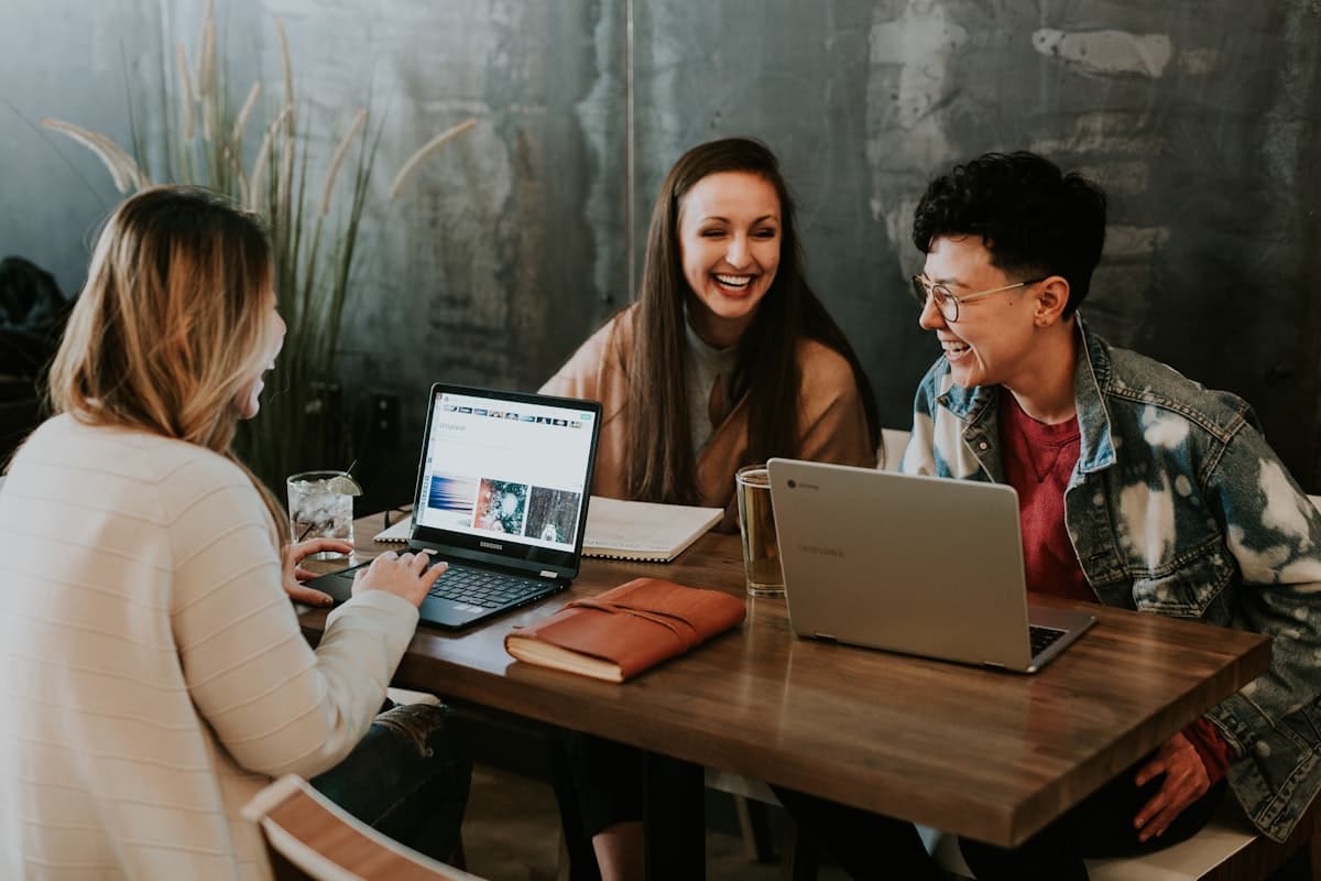 Three professionals working together at a café table with laptops